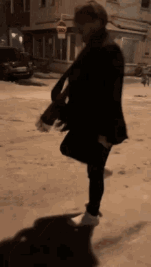 a person is standing on a snowy street with a no parking sign in the background .