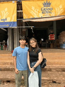 a boy and a girl are posing for a picture in front of a sign that says grand royal lifestyle