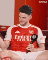 a man wearing a red emirates fly better jersey