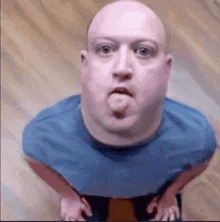 a bald man in a blue shirt is making a funny face .