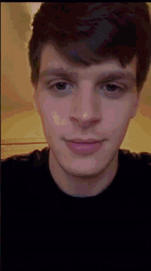 a young man in a black shirt looks at the camera