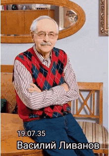 a man in a plaid vest is sitting on a chair with his arms crossed