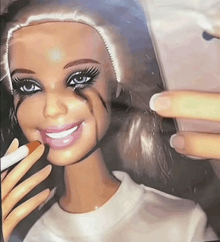 a barbie doll with makeup on her face is smiling and holding a cell phone