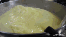 a pot of yellow liquid is being stirred with a spoon and the words made in animatica are visible in the corner