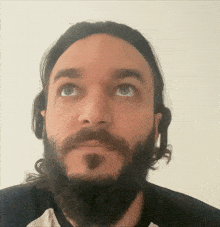 a man with long hair and a beard looks up