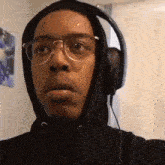 a man wearing glasses and headphones is taking a selfie .