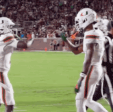 two football players are giving each other high fives on the field .