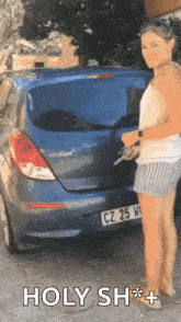 a woman is standing in front of a blue car that says holy sh * t on it