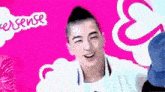 a man is laughing in front of a pink background with a speech bubble .