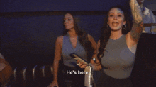 two women are standing next to each other with the words he 's here on the bottom