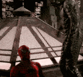 a man in a spiderman costume stands in front of a fence