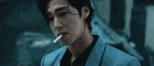 a man in a blue jacket is smoking a cigarette