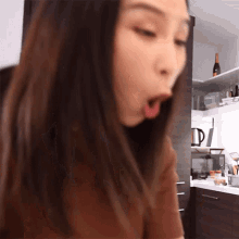 a woman is sitting in a kitchen with her mouth wide open