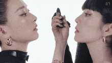 a woman is applying makeup to another woman 's face with the letter s visible