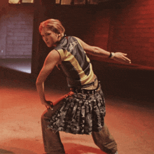 a woman wearing a black vest with a yellow stripe on the back is standing in a dark room