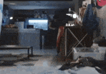 a blurry picture of a room with a lot of clothes on the floor and a man standing in the background .