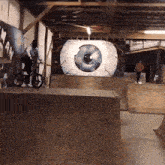 a person riding a bike in front of a large eye painting