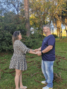 a man and a woman hold hands in a park