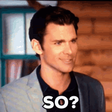 a man in a suit and black shirt is making a funny face and says so .