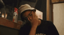 a man wearing a hat and glasses is talking on a cell phone in a restaurant .