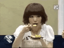 a young woman is eating a piece of food with a fork .