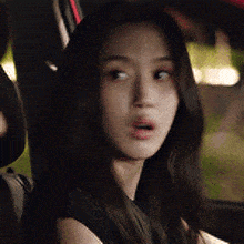 a woman is sitting in the back seat of a car looking at the camera .