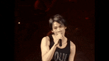 a man singing into a microphone while wearing a soul tank top