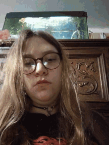 a woman wearing glasses and a choker is laying down
