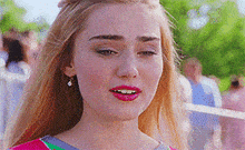 a close up of a woman 's face with long blonde hair and pink lipstick .