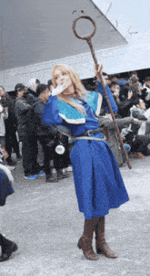 a woman in a blue costume is holding a cane