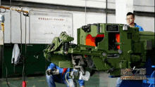 two men working on a machine with cctv 2 on the bottom left