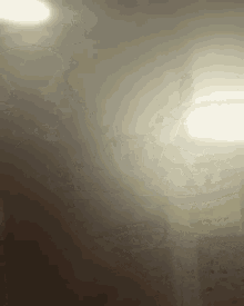 a blurred image of a person standing in a dark room with a light shining through the smoke .