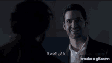 a man in a suit is smiling while talking to another man in a dark room .
