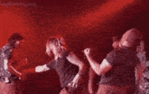 a group of people are dancing on stage in front of a red light .