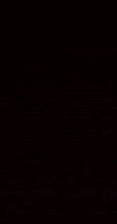 a group of people are dancing in a dark room . one of the people is wearing a green shirt .