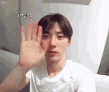 a young man in a white t-shirt waves his hand