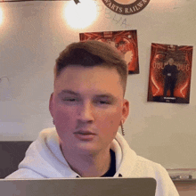 a young man sitting in front of a laptop with a poster on the wall behind him that says oculus