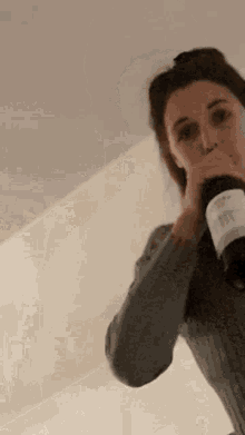 a woman is holding a bottle of wine in her hand and drinking from it .