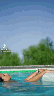 a woman is laying on her back in a swimming pool