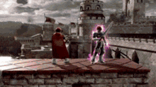 a man in a red cape is standing on a brick wall next to a castle .