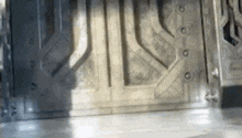 a close up of a metal door in a room with a light coming through it .