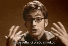 a man wearing glasses is making a funny face with his hands outstretched in a foreign language .