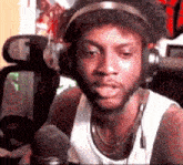 a man wearing headphones and a tank top is talking into a microphone .
