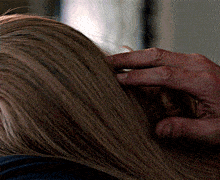 a person is touching a woman 's hair with their hand
