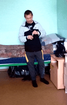 a man wearing a nike jacket is standing in a bedroom