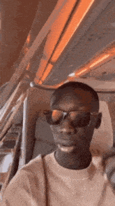 a man wearing sunglasses is sitting on a plane and making a funny face .