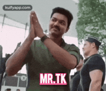 a man in a green shirt is clapping his hands and says mr. tk .