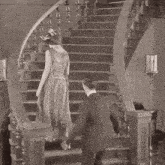 a black and white photo of a man and woman walking down stairs