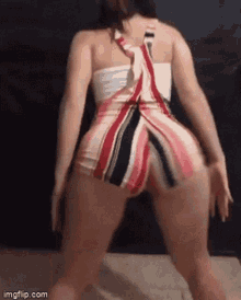 a woman in a striped dress and shorts is dancing on a floor .