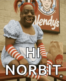 a wendy 's sign is behind a person dressed in a wendy 's costume